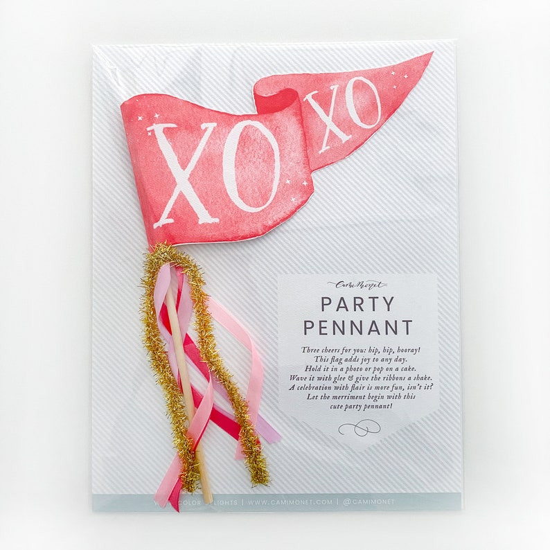 Puede incluir: Un bander&iacute;n de fiesta rosa y blanco con la palabra "XOXO" en letras blancas. El bander&iacute;n est&aacute; sujeto a un palo con serpentinas de purpurina rosa, dorada y blanca. El texto de la tarjeta dice "Bander&iacute;n de fiesta" e incluye una breve descripci&oacute;n del producto.