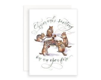 Könnte beinhalten: Eine Aquarellillustration von fünf Streifenhörnchen, die Marshmallows am Lagerfeuer rösten. Der Text "Chipmunks roasting on an open fire" ist in grüner Kursivschrift geschrieben.