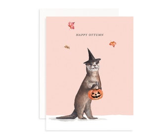Könnte beinhalten: Ein süßes Otter, das einen Hexenhut trägt und eine Kürbislaterne hält. Der Hintergrund ist hellrosa mit fallenden Blättern. Der Text "HAPPY OTTUMN" steht in Schwarz oben auf der Karte.