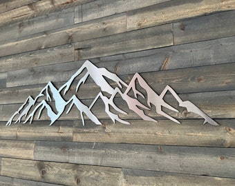 May include: A silver metal mountain range wall decor with a rustic wood background.