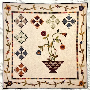 May include: A beige quilt with a floral design in the center. The floral design features a brown vase with a geometric pattern and green stems with red, orange, and blue flowers. The quilt is surrounded by a brown vine border with small red and blue berries.