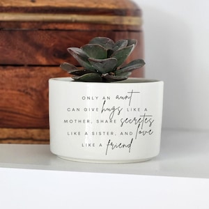May include: White ceramic planter with a succulent plant. The planter has a quote that reads "Only an aunt can give hugs like a mother, share secrets like a sister, and love like a friend."