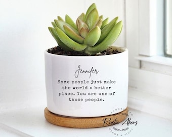 May include: A white ceramic planter with a succulent plant. The planter has the name "Jennifer" and a quote: "Some people just make the world a better place. You are one of those people." It sits on a round, wooden coaster.