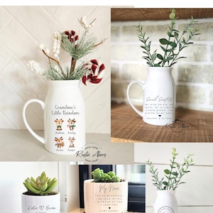 May include: A collection of white ceramic vases and planters with various designs and text. One vase says "Grandma's Little Reindeer" with reindeer illustrations. Another says "Soul Sister." Other planters have text like "My Niece" and "Katie & Brian."