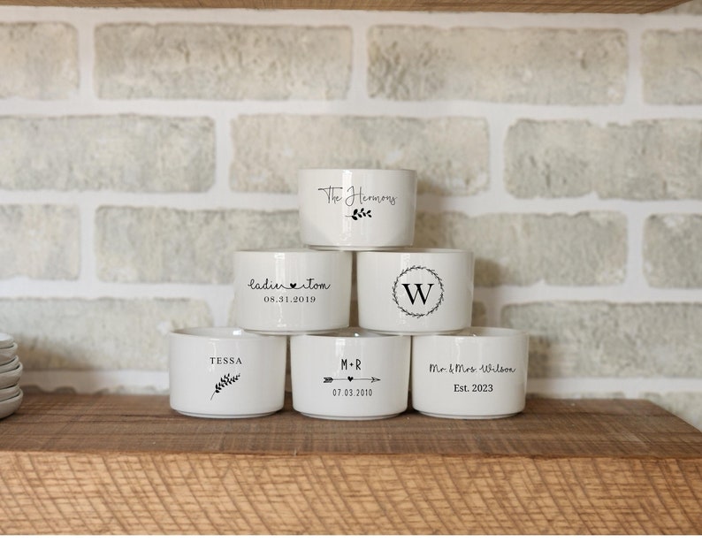 Pu&ograve; includere: Sei portacandele in ceramica bianca con diversi testi e disegni personalizzati. Il testo include "The Harmony", "ladinitom 05.31.2019", "(W)", "TESSA", "M-R 07.03.2010" e "Mr & Mrs Wilson Est. 2023".