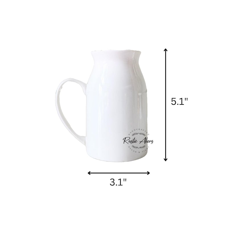 May include: A white ceramic pitcher with a handle, measuring 5.1 inches tall and 3.1 inches wide. The pitcher has a ruffled top and a curved handle. The words "Rustic Akers" are printed on the side.