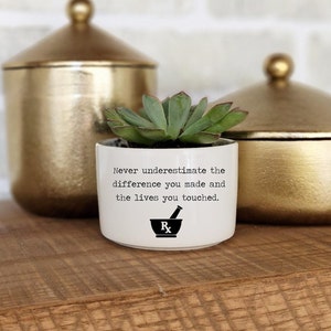 May include: White ceramic planter with a succulent plant and the text "Never underestimate the difference you made and the lives you touched." with a black mortar and pestle symbol.