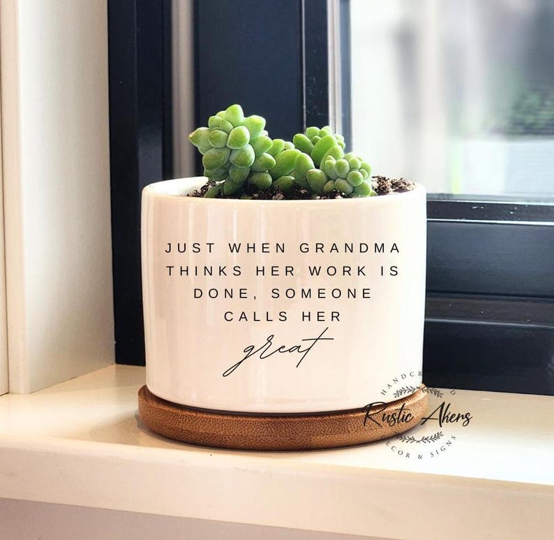 May include: White ceramic planter with a bamboo base. The planter has a quote that reads "Just when Grandma thinks her work is done, someone calls her great".