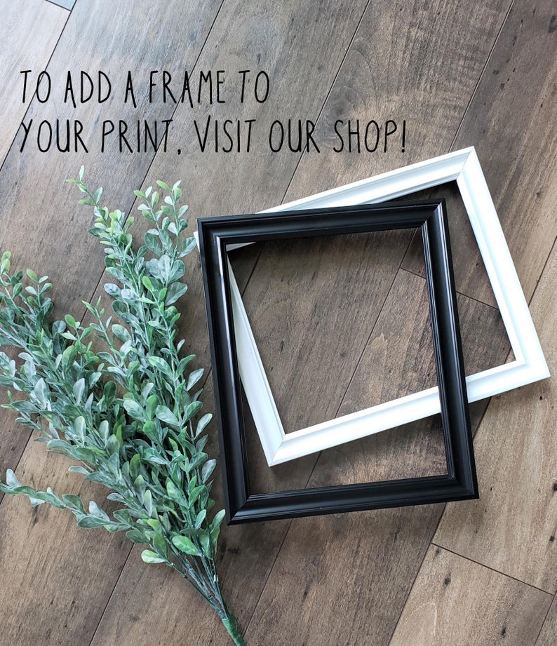 May include: Two picture frames, one black and one white, are lying on a wood floor. The frames are overlapping. The text "To add a frame to your print, visit our shop!" is written on the floor above the frames.