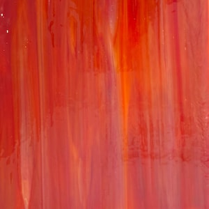 May include: Abstract glass art piece with a vibrant blend of red, orange, and white hues. The colors are layered in vertical streaks, creating a dynamic and textured appearance. The glass has a glossy finish, enhancing the depth and luminosity of the colors.