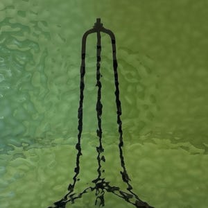 May include: Abstract art piece featuring a black, stylized, vertical structure against a green and yellow background. The structure has a unique, elongated shape with three vertical lines and a top element.