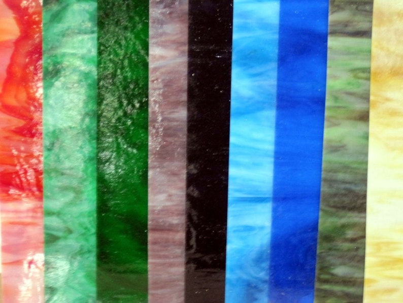 Puede incluir: Primer plano de una variedad de piezas de vidrio emplomado en diferentes colores, incluyendo rojo, verde, azul y amarillo. El vidrio es texturizado y tiene un efecto brillante.
