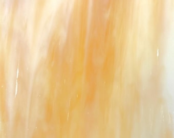 Puede incluir: Primer plano de una lámina de vidrio coloreado con un patrón fluido. El vidrio presenta una mezcla de colores cálidos, incluyendo tonos de amarillo, naranja y blanco. Los colores están mezclados, creando un efecto veteado. El vidrio es translúcido.