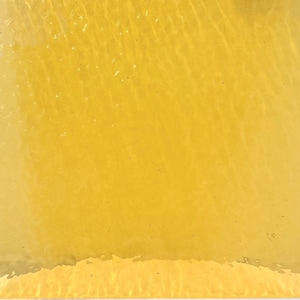 May include: A close-up shot of a textured, yellow surface. The color is a vibrant, sunny yellow, with subtle variations in tone and texture. The surface appears to be slightly reflective, with hints of light and shadow creating a sense of depth.