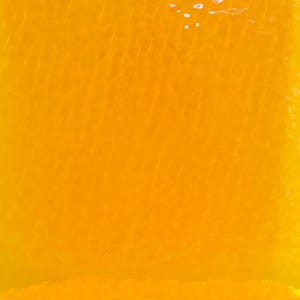 May include: A close-up of a textured, amber-colored surface. The surface has subtle wave-like patterns and a glossy finish. The color is a vibrant, warm yellow-orange, reminiscent of sunlight or honey.