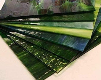 May include: A stack of green, blue, and clear glass tiles. The tiles are arranged in a fan shape, with the green tiles on the bottom and the clear tiles on the top.
