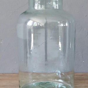 May include: A clear glass jar with a wide mouth and a green rim. The jar is empty and has a slight green tint.