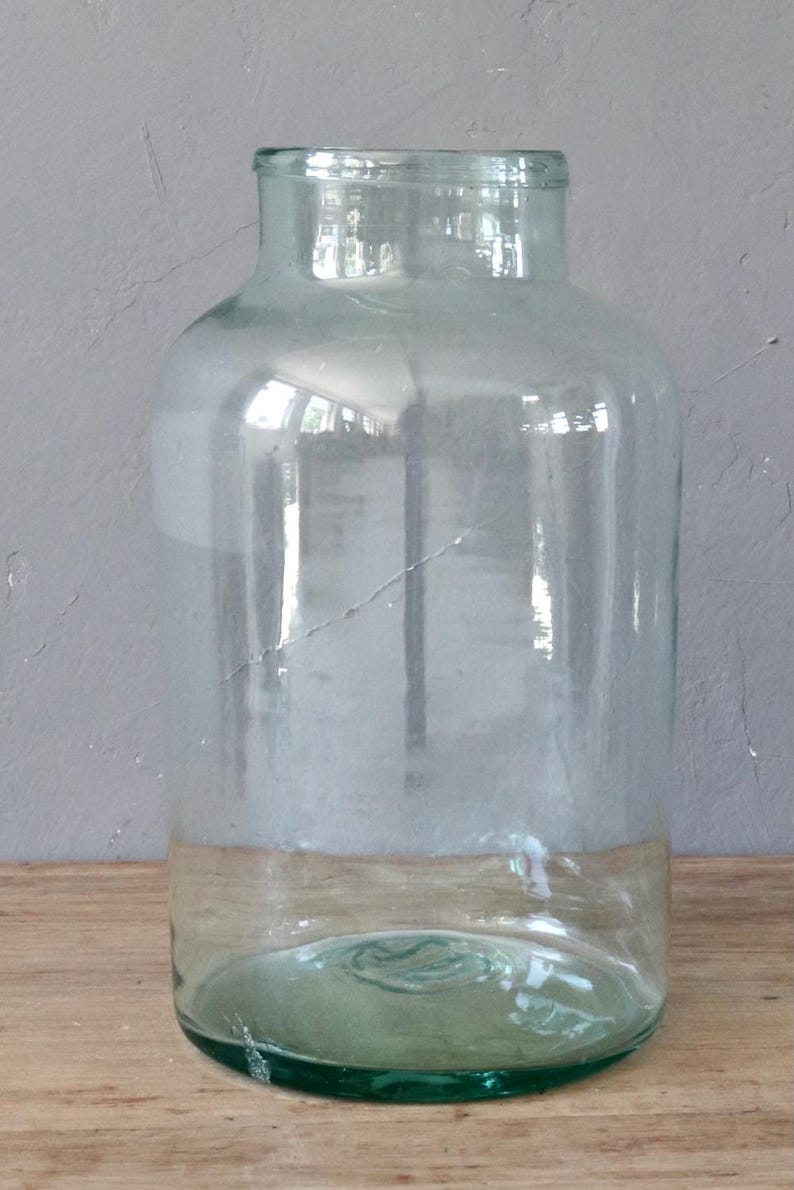 May include: A clear glass jar with a wide mouth and a green rim. The jar is empty and has a slight green tint.