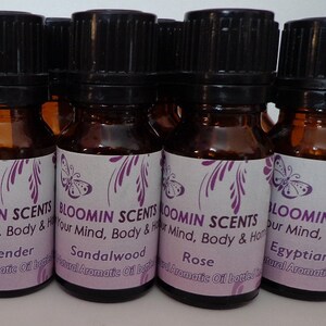 May include: Six small brown glass bottles with black lids and labels. The labels feature a purple butterfly design and the text "BLOOMIN SCENTS Your Mind, Body & Home" with the scent name below. The scents are Lavender, Sandalwood, Rose, and Egyptian Musk.