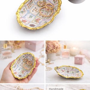 May include: An oval-shaped oyster shell trinket dish featuring a decoupage interior with a grid of floral and botanical illustrations. The edges of the shell are finished with a textured gold leaf trim. The dish holds three gold-toned rings.