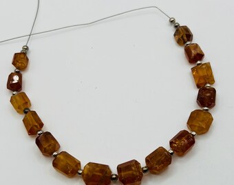 May include: A strand of faceted, amber-colored gemstone beads. The beads are rectangular with rounded edges and are strung together with small silver-colored beads. The gemstones have a warm, translucent appearance.