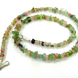 Peut inclure: Un collier composé de petites pierres de tourmaline de forme irrégulière, dans des tons de rose, de vert et de transparent. Le collier est doté d'un fermoir argenté et est présenté sur fond blanc.