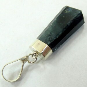 May include: A dark green, rectangular pendant with a silver-colored metal cap and loop. The pendant has a faceted, geometric shape and a polished finish. The loop is attached to the cap with a small ring. The pendant is likely a gemstone.