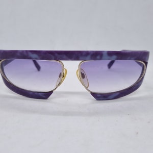 Könnte beinhalten: Lila und blaue marmorierte Sonnenbrille mit goldenen Akzenten und Verlaufsgläsern.