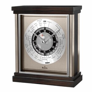 May include: A silver and black world time clock with a wood base. The clock face features a map of the world with city names and time zones. The clock has a silver frame and a black base with a wood grain pattern. The clock is made by Bulova.