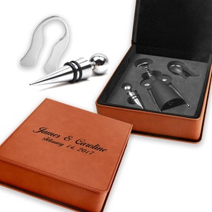 May include: A brown leatherette gift box with a silver wine opener set inside. The box is engraved with the text "James & Caroline February 14, 2017".
