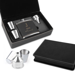 May include: A black leather gift box with a silver flask, two shot glasses, and a funnel. The flask is engraved with the initial "J" and the name "John Kennedy".