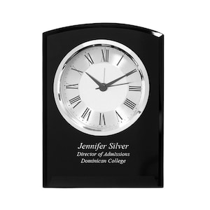 May include: Black rectangular clock with a silver face and Roman numeral hour markers. The clock is on a black base with the inscription "Jennifer Silver, Director of Admissions, Dominican College".