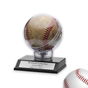 May include: A baseball encased in a clear plastic dome sits on a black base with a silver plaque that reads "William Longing Game Ball June 15, 2013".