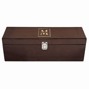 May include: A dark brown wooden box with a silver latch. The top of the box has a gold monogram of the letter "M" in a square frame.