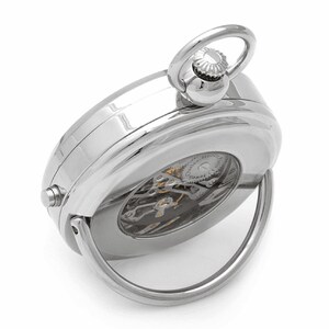 May include: A silver pocket watch with a clear back revealing the intricate mechanical workings. The watch has a hinged loop for attaching to a chain.