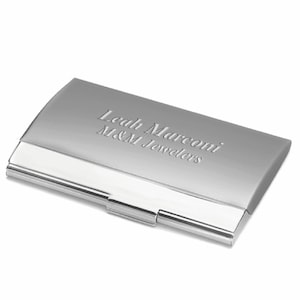 May include: Silver metal business card holder with engraved text "Leah Marconi M&M Jewelers"