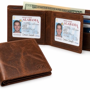 May include: A brown leather bifold wallet with a distressed finish and the embossed initials JFK on the front. The open wallet displays two clear ID windows containing Alabama driver licenses, multiple card slots, and a twenty-dollar bill.
