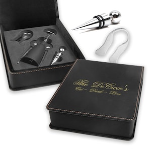 May include: Black leatherette gift box with gold stitching and the text "The De Cicco's Eat - Drink - Love" engraved on the top. The box contains a wine opener set with a corkscrew, foil cutter, bottle stopper, and a wine ring.