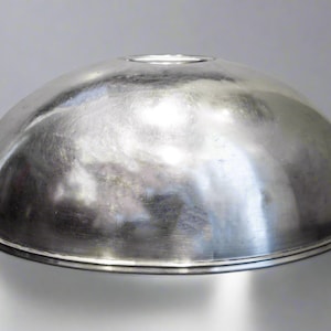 May include: A silver-colored, dome-shaped metal bowl with a circular opening at the top. The bowl has a reflective surface and a rounded base. The object is likely a kitchen or serving item.
