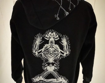 May include: Black hoodie with a white skeleton graphic on the back. The hood features white stitching and a design of crossed bones. The text "Born in Dust" is printed at the bottom of the hoodie.