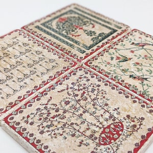 Könnte beinhalten: Vier quadratische Untersetzer mit aufwendigen Designs. Jeder Untersetzer hat einen cremefarbenen Hintergrund mit einem anderen Muster: ein Baum, Vögel auf Ästen, florale Motive und ein Pfeildesign. Rote Ränder umrahmen jeden Untersetzer.