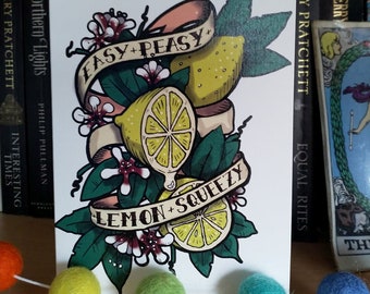 May include: A white card with a colorful illustration of lemons and flowers. The text "EASY+PEASY+LEMON+SQUEEZY" is written on the card.