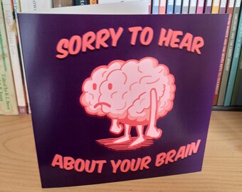 May include: A purple card with a pink cartoon brain with a sad expression. The card says "Sorry to hear about your brain."