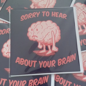 May include: A greeting card with a cartoon brain with a sad expression. The card has the text "Sorry to hear about your brain" in red letters on a black background.