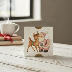 Op de afbeelding: Een vierkante kaart met een vintage illustratie van de Kerstman en een rendier. De Kerstman draagt een roze pak en houdt de teugels van het rendier vast. De kaart heeft een witte achtergrond met grijze stippen en gouden accenten.