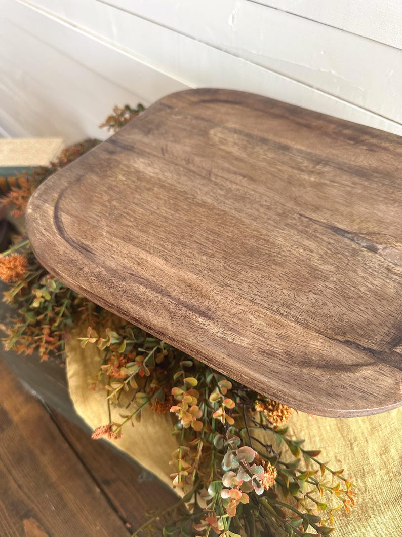 May include: A rectangular wooden serving tray with rounded corners and a smooth, dark brown grain finish. The tray features a shallow recessed surface with a defined border edge, showcasing natural wood textures and variations in color.