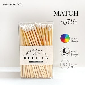 May include: A clear plastic box filled with approximately 100 wooden matches with white tips. The box has a label that reads "MADE MARKET CO. -100 CT. 3.5 INCHES REFILLS SAFETY MATCHES". The image also includes a color wheel with 25 color options, a red and white fire icon with the text "Striker Included (w/sticky back)", and a white circle with the number "100" and the text "Approx. Qty."