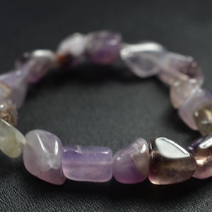 May include: A purple and clear crystal bracelet made of tumbled stones. The bracelet is made of amethyst and citrine.