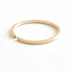 May include: A simple gold ring with a small gap in the band.