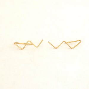 May include: A pair of gold ear cuffs with a zig-zag design.